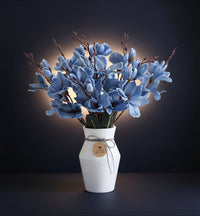 Bouquet of blue flowers in a white vase on a white background